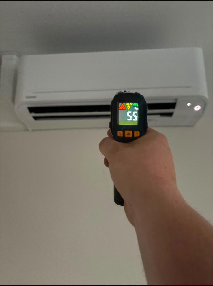 Engineer checking the temperature of a domestic air conditioning unit